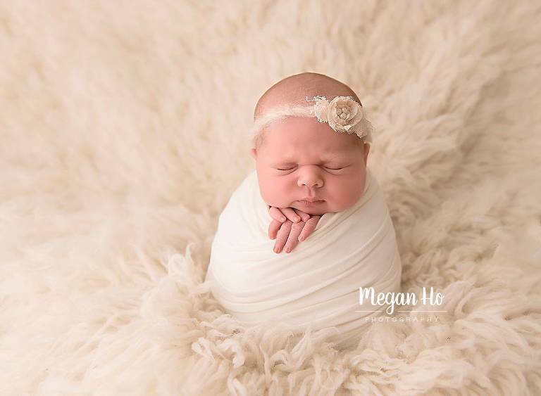 baby girl wrapped in white with flower tieback newborn session new hampshire