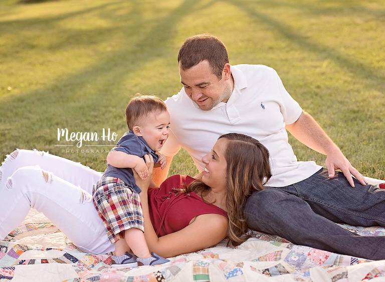 southern nh family session on summer night adorable family of three laughing and sitting on large quilt