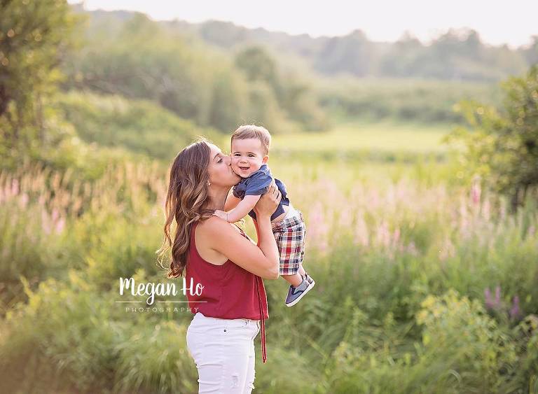 beautiful mama kissing baby boy on cheek in beautiful Londonderry nh family session on summer night