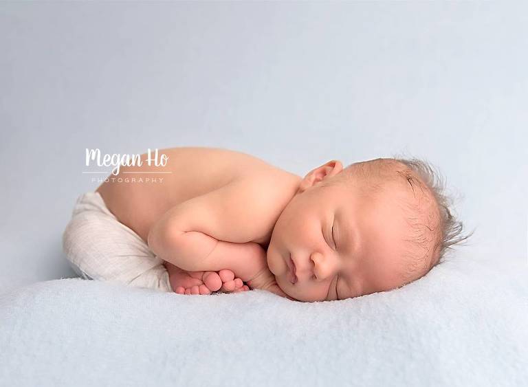 adorable new hampshire baby boy sleeping on blue blanket with toes showing