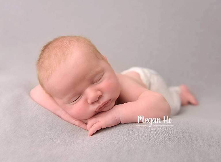 head on hands sleeping newborn boy on gray background in new hampshire session