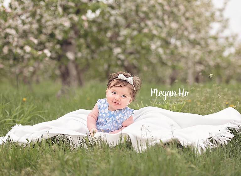 baby girl sitting on white blanket in nh apple orchard