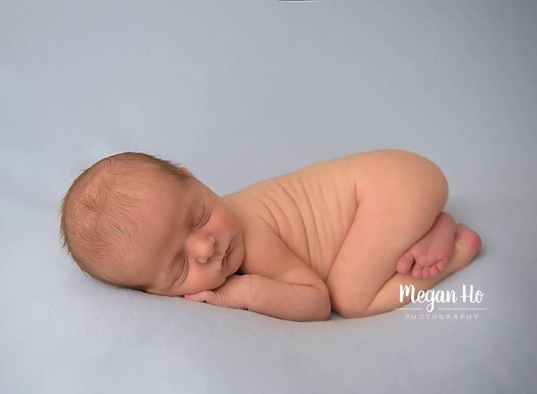snuggly sleeping baby boy on blue newborn session nh