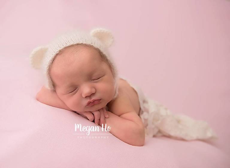 newborn baby girl on pink blanket with white bear bonnet