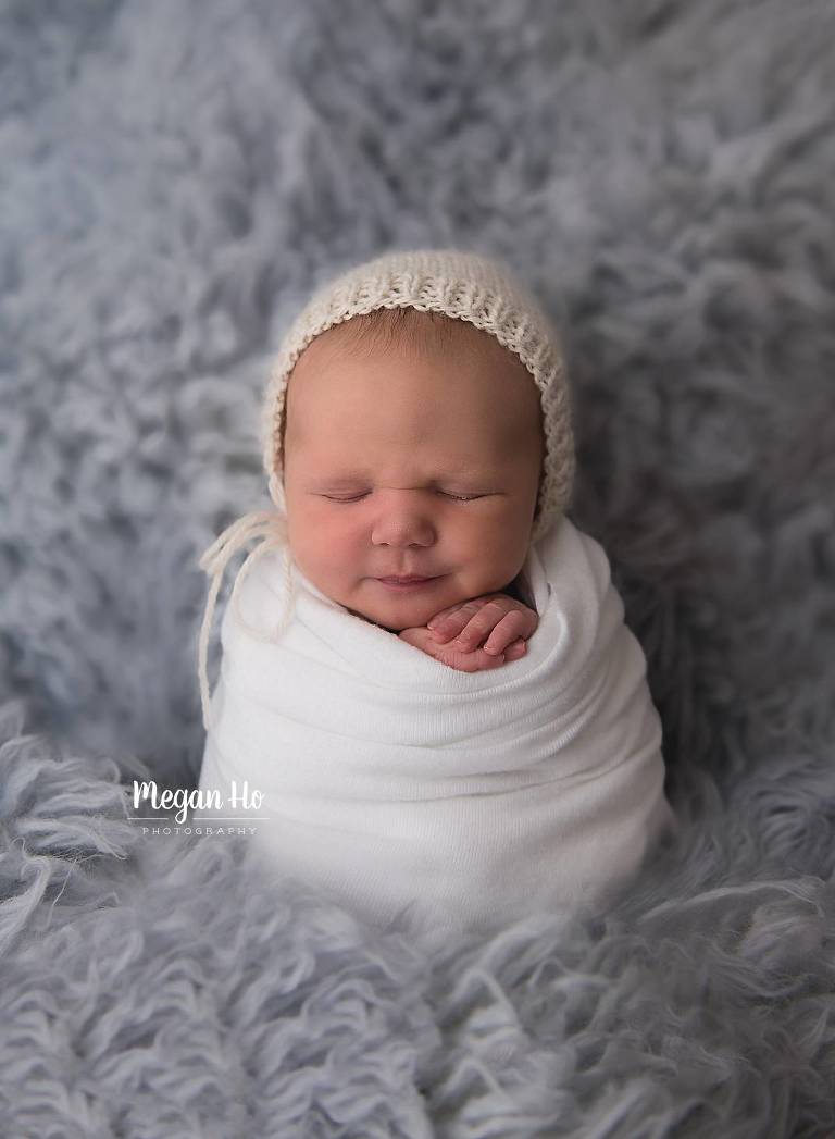 adorable swaddled baby on blue wrapped on fuzzy rug