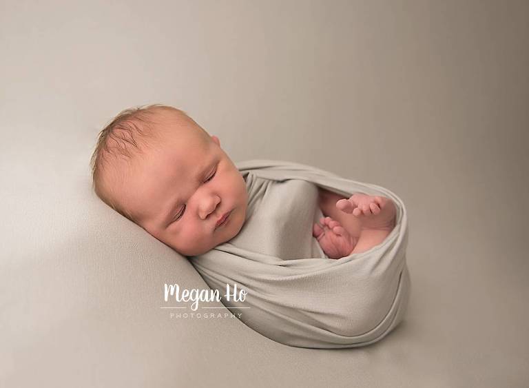 little baby boy wrapped in sage green sleeping