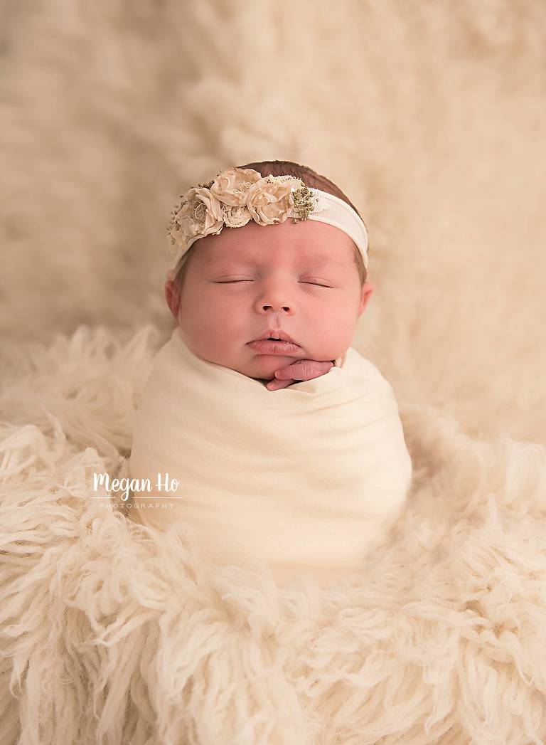 beautiful wrapped baby girl upright sleeping on white rug
