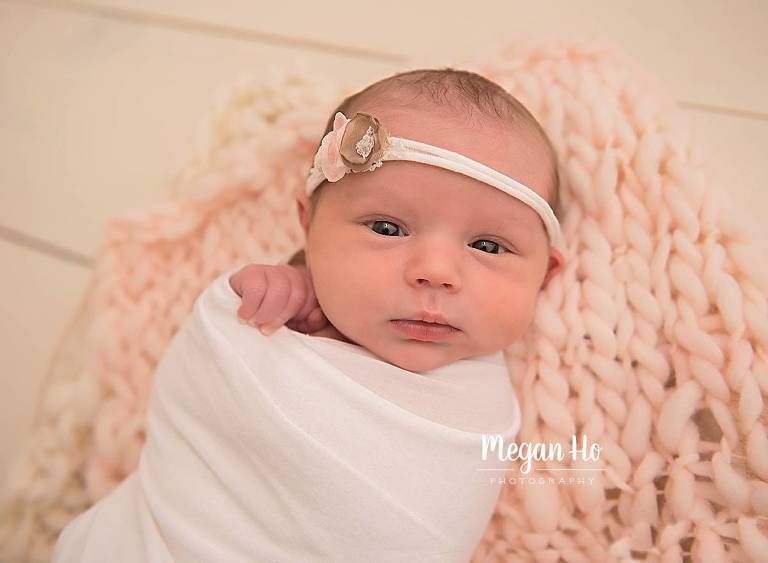 newborn girl wrapped in white with eyes wide open in bedford nh studio