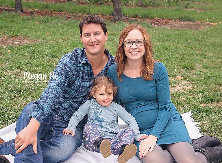 family of soon to be four in blue sitting on blanket in fall session