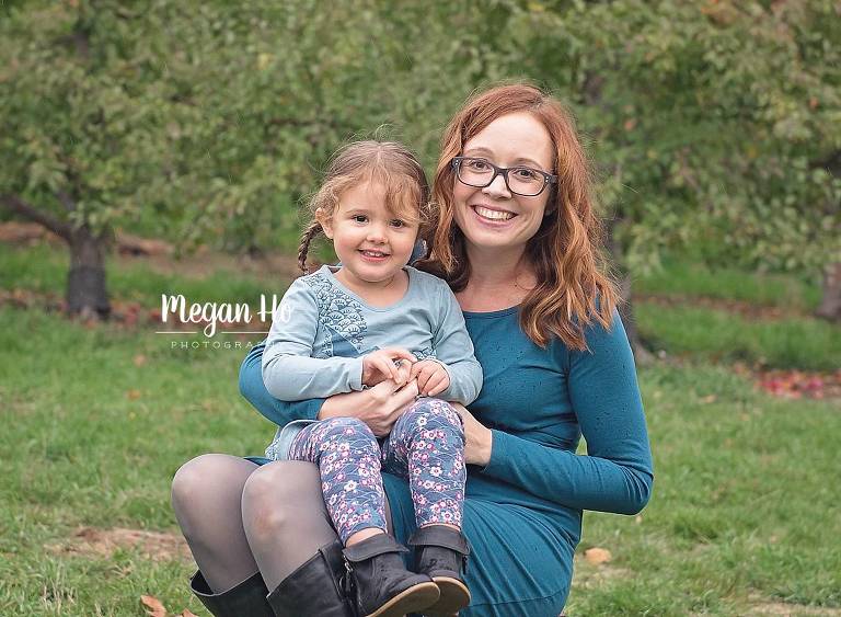 toddler girl in blue sitting on moms lap in nh apple orchard