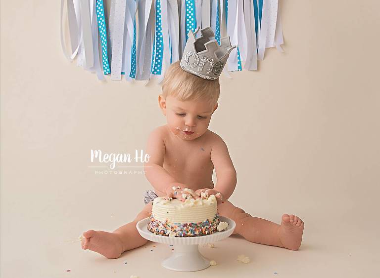 one year boy sitting by cake with grey one crown and blue banner