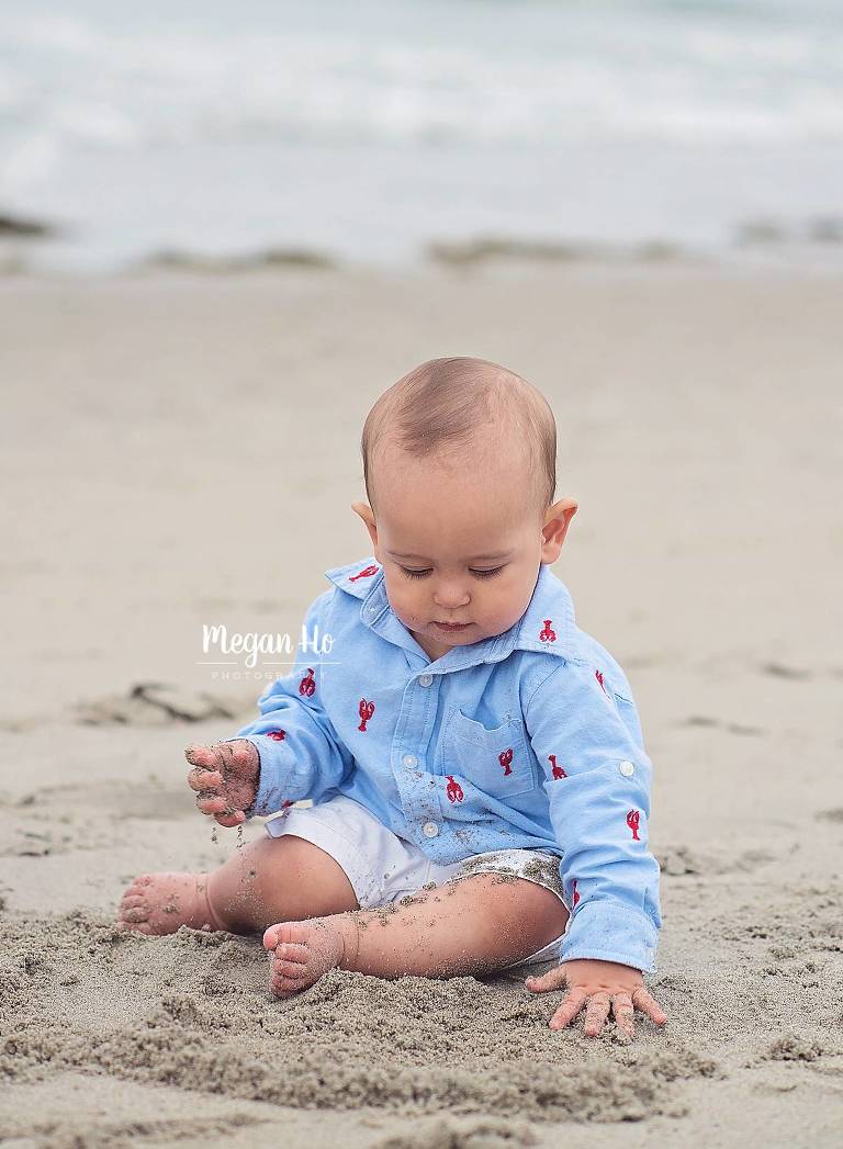 nh one year old sitting covered in sand on beach
