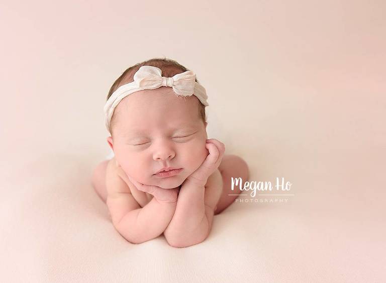 nh newborn baby girl sleeping in froggy pose with pink bow