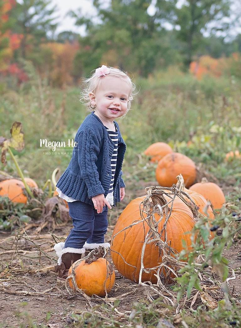 smiling girl standing in front of big pumpkins in Londonderry nh