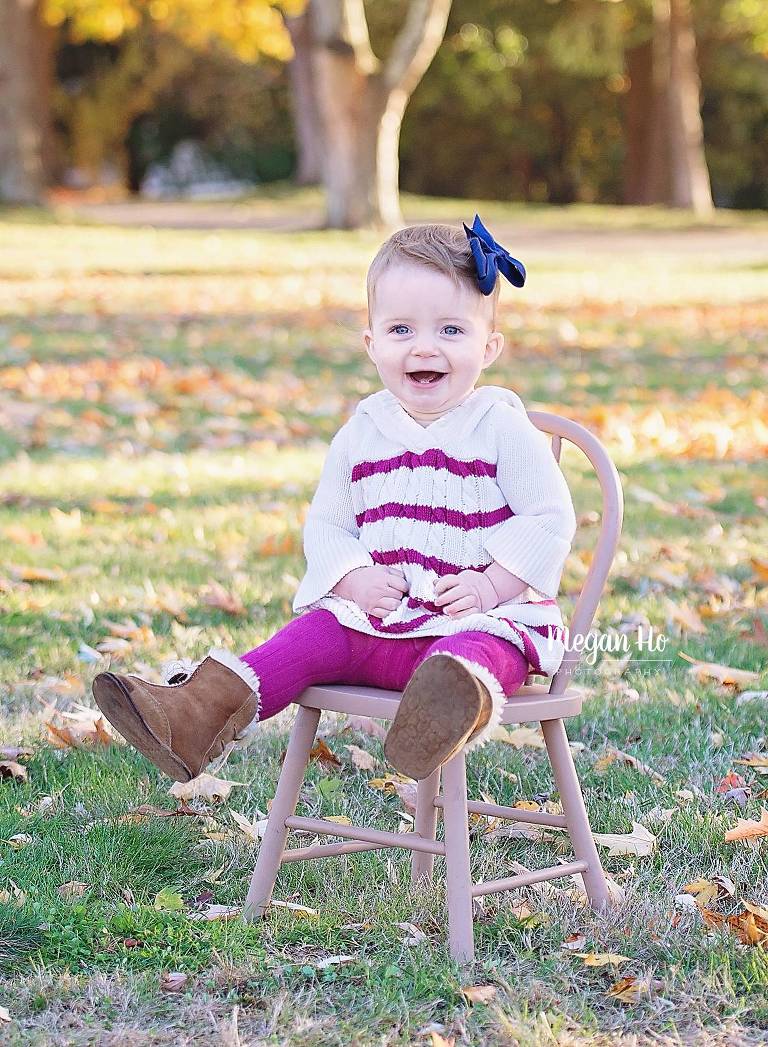 little girl sitting on chair in pink and white sweater in fall park