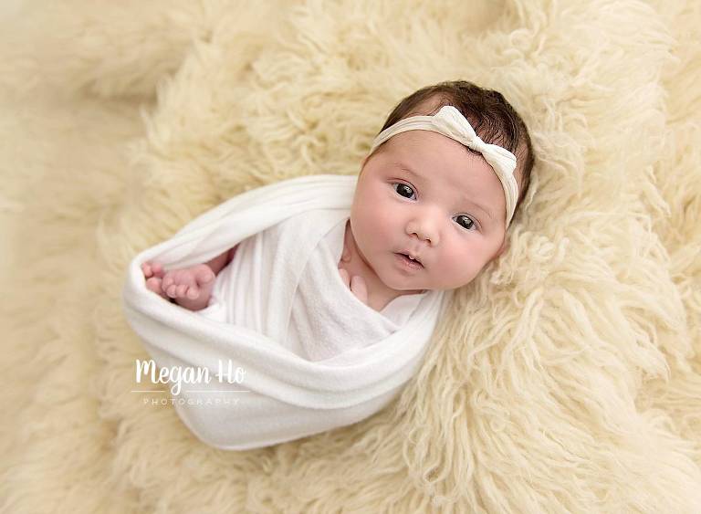 wrapped and awake newborn baby girl on rug in bedford nh studio
