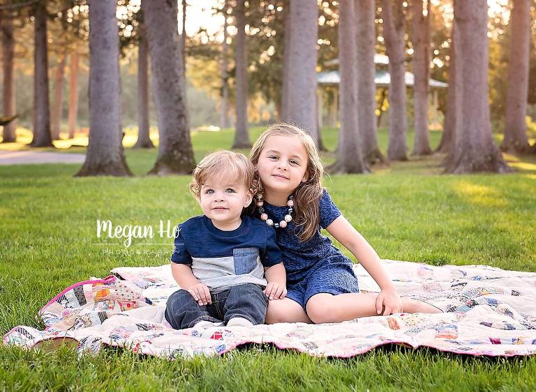 brother and sister sitting on a quilt in park at evening in southern nh