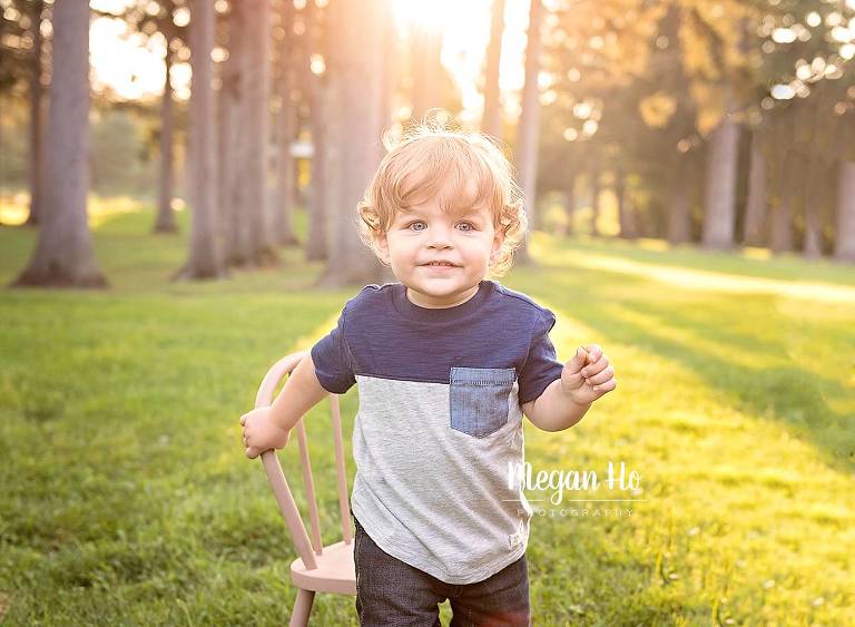 golden light above little boys head smiling with blue and grey shirt