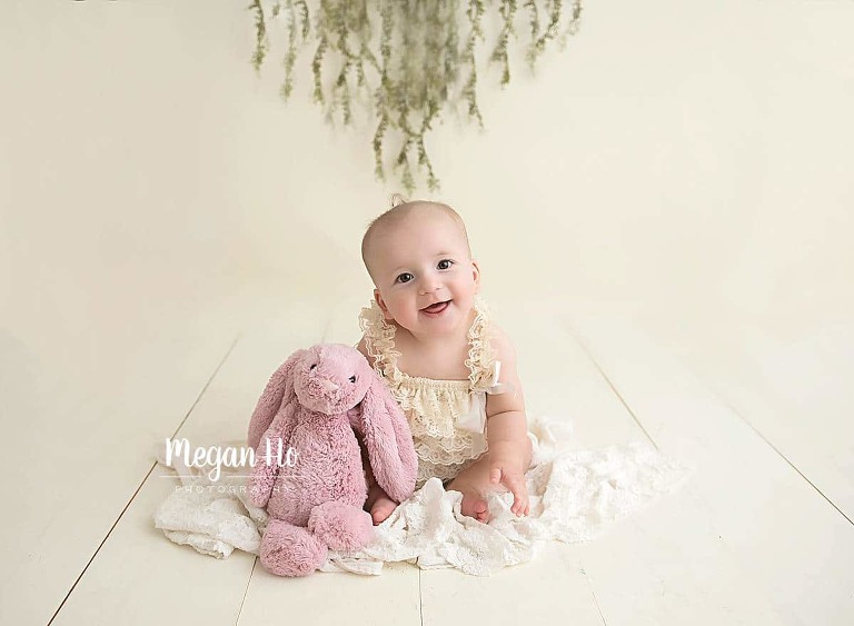 sitter milestone session in bedford nh baby girl in cream romper sitting on lace with pink bunny