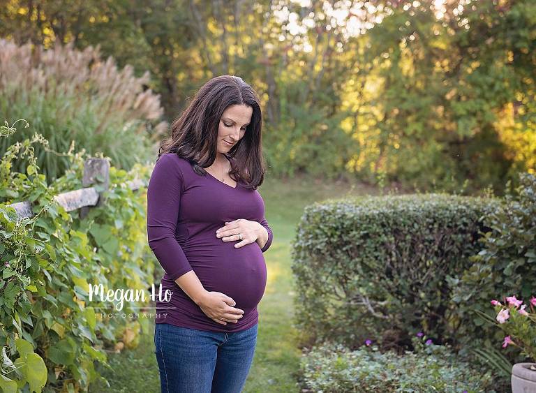 pregnant mom looks lovingly down at belly in nh field