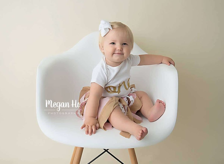 smiling one year blonde girl in white chair in bedford nh studio