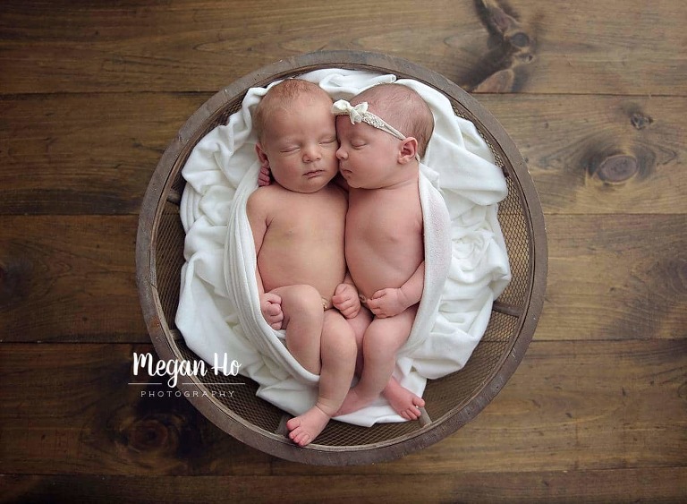 twin babies wrapped together in white laying in wood bowl on wooden floor nh studio session