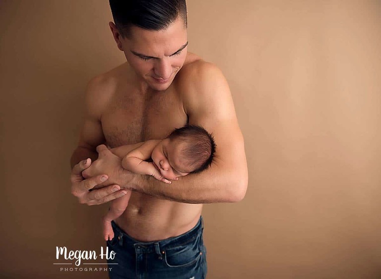 Dad with muscles and no shirt cuddling newborn baby boy in Bedford NH