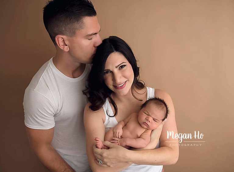 Mom and dad snuggling their newborn baby boy in studio session