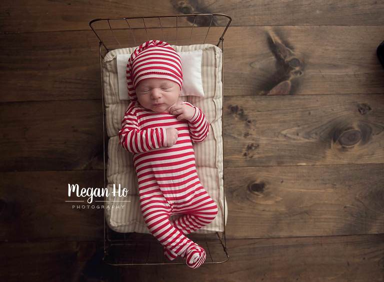 sleepy baby on wire bed with Christmas striped jammies on in southern nh