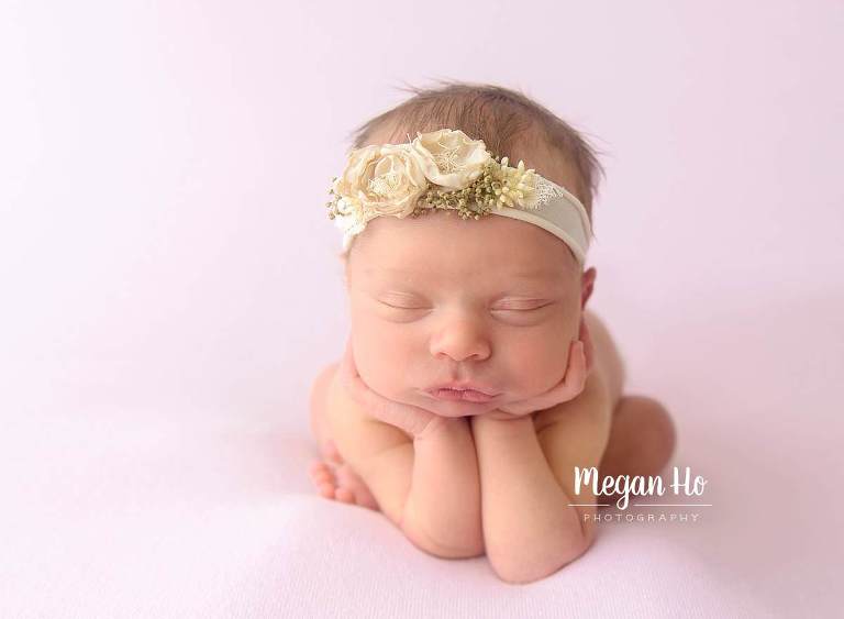 sleeping baby girl in cream flower headband on pink blanket froggy pose southern nh