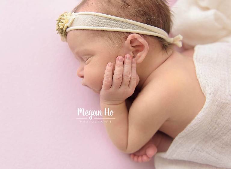 sleeping baby girl with fingers resting on cheek in studio session