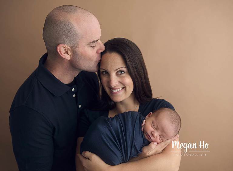 happiest mom and dad with brand new baby boy on light brown background