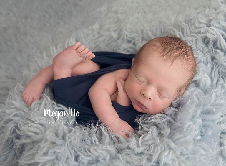 southern nh newborn baby boy wrapped in navy wrap on light blue rug