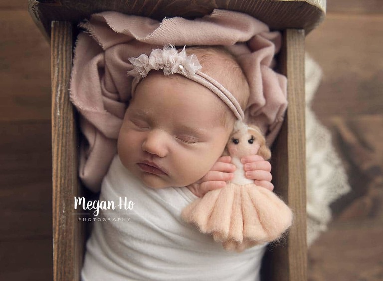 baby girl sleeping in little bed with dainty pink tieback and ballerina doll