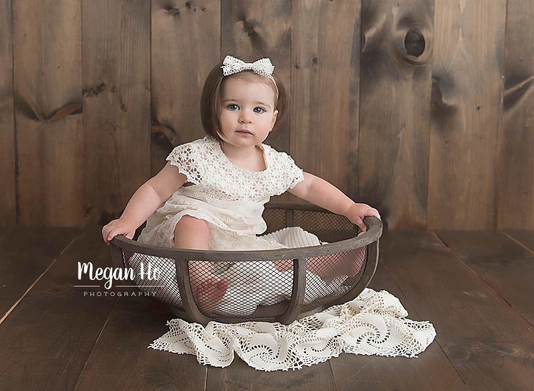 girl in white dress and bow sitting in a wooden bowl on lace in bedford nh