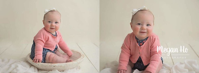 adorable 6 month girl sitting on white wood with white bow