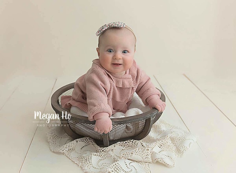 blue eyed girl sitting up in wood bowl on white backdrop