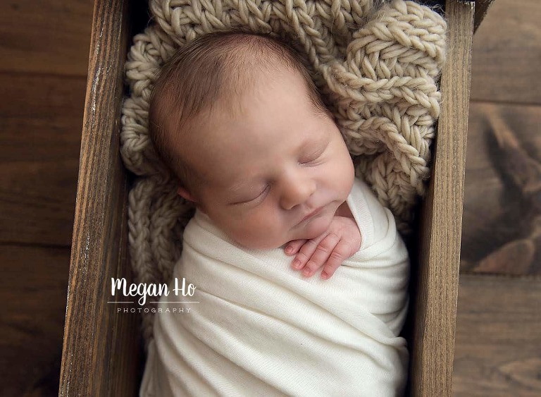 adorable wrapped up baby boy in little wooden bed in before nh
