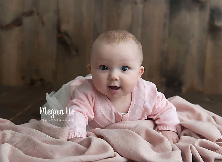 six month baby girl pushing up in pretty pink on wood backdrop in Bedford NH