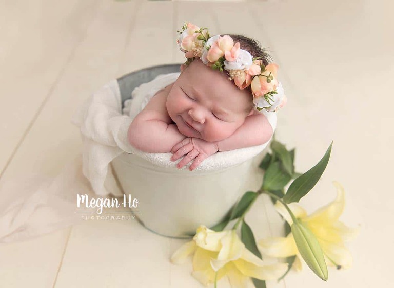 adorable baby girl in white bucket with lilies and flower halo