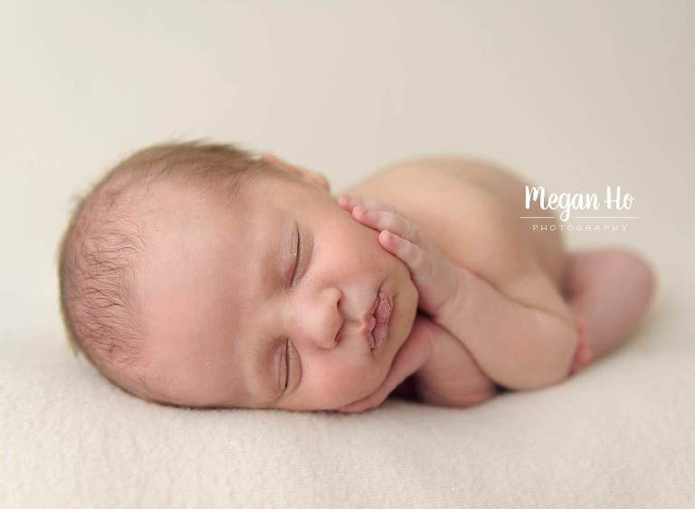 timber pose with newborn boy laying with face in hands on blanket