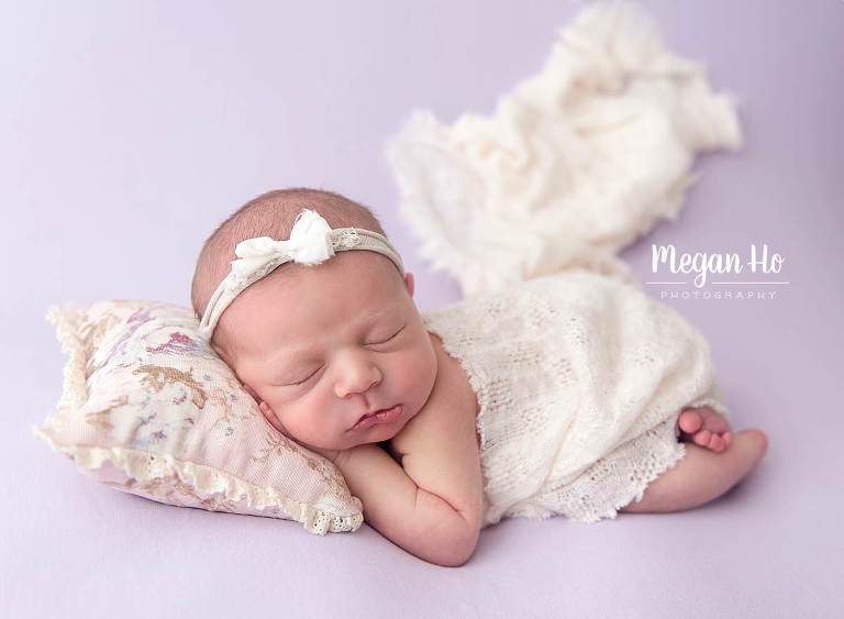 baby girl sleeping on little pillow covered in lace on purple