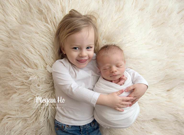 big brother happily holding baby boy in nh newborn session