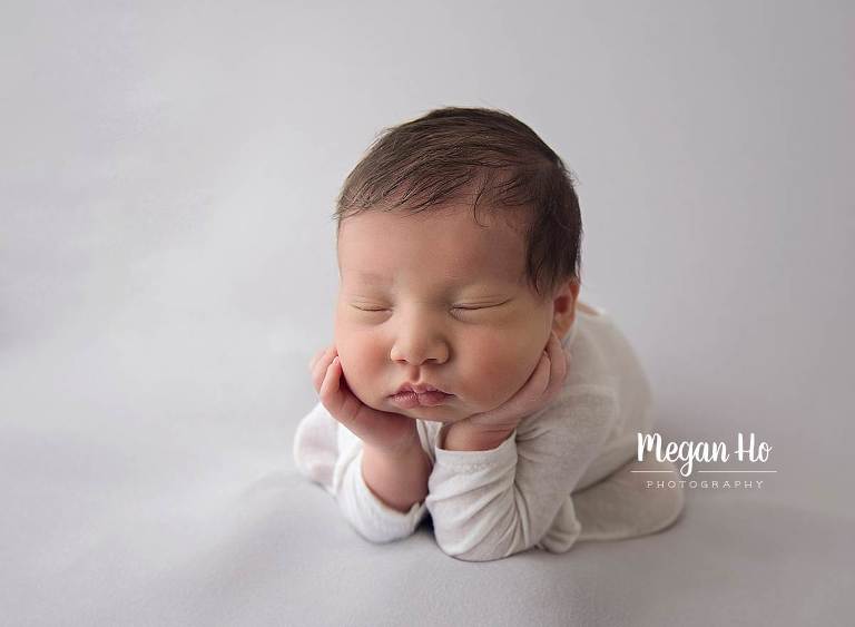 froggy pose with white romper with feet on grey baby boy with brown hair