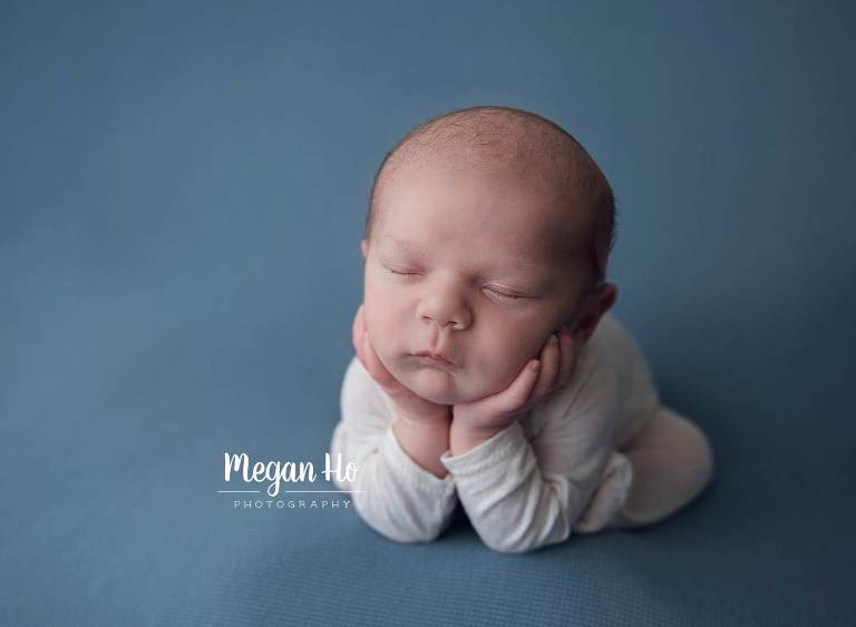froggy pose with newborn boy in white outfit on blue blanket