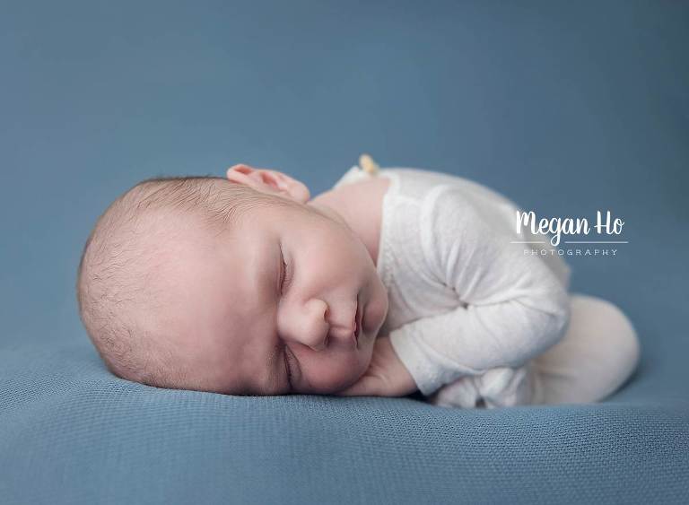 curled up little boy sleeping on blue blanket with little toes showing