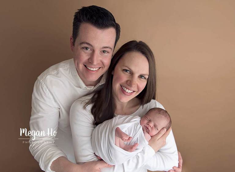 family of three in their newborn session all in white