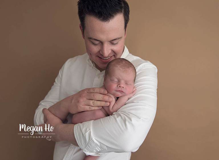 dad smiling with baby boy in crook of arm In nh studio