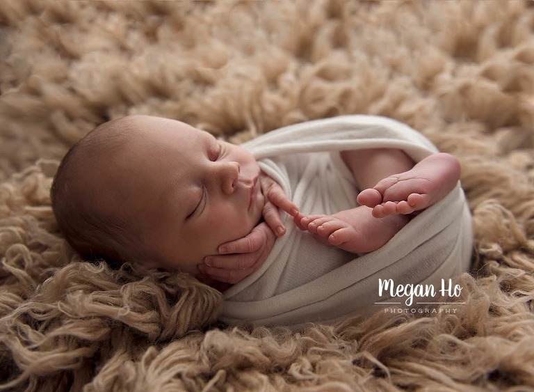 bedford new Hampshire baby boy wrapped with feet out backlit on tan rug