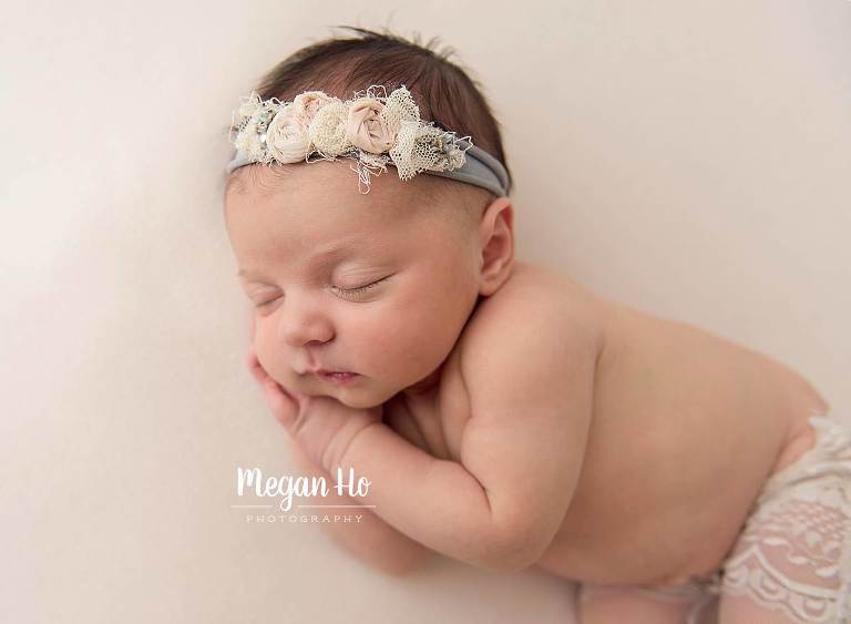 infant girl sleeping on side in little lace pants with beautiful flower tieback